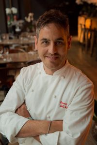 mezzo busto di uomo sorridente con casacca bianca da chef 